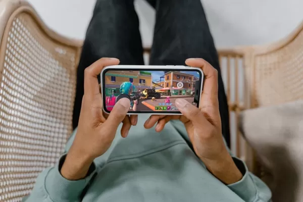 Ein Paar Hände, die ein Telefon halten, das Fortnite mit einem Magnetauslöser spielt, der am Telefon angeschlossen ist